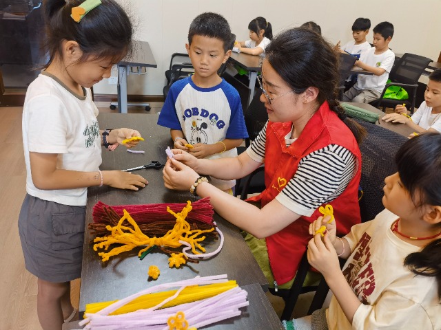 7月12日，在泰州市海陵區(qū)城東街道林湖社區(qū)，泰州市大浦小學(xué)“綠葉”暑期公益班的老師正在教孩子們一起做手工2（拍攝者：泰州市大浦中心小學(xué)  陳惠婷）.jpg